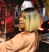 a woman is posing for a picture in front of a graffiti wall